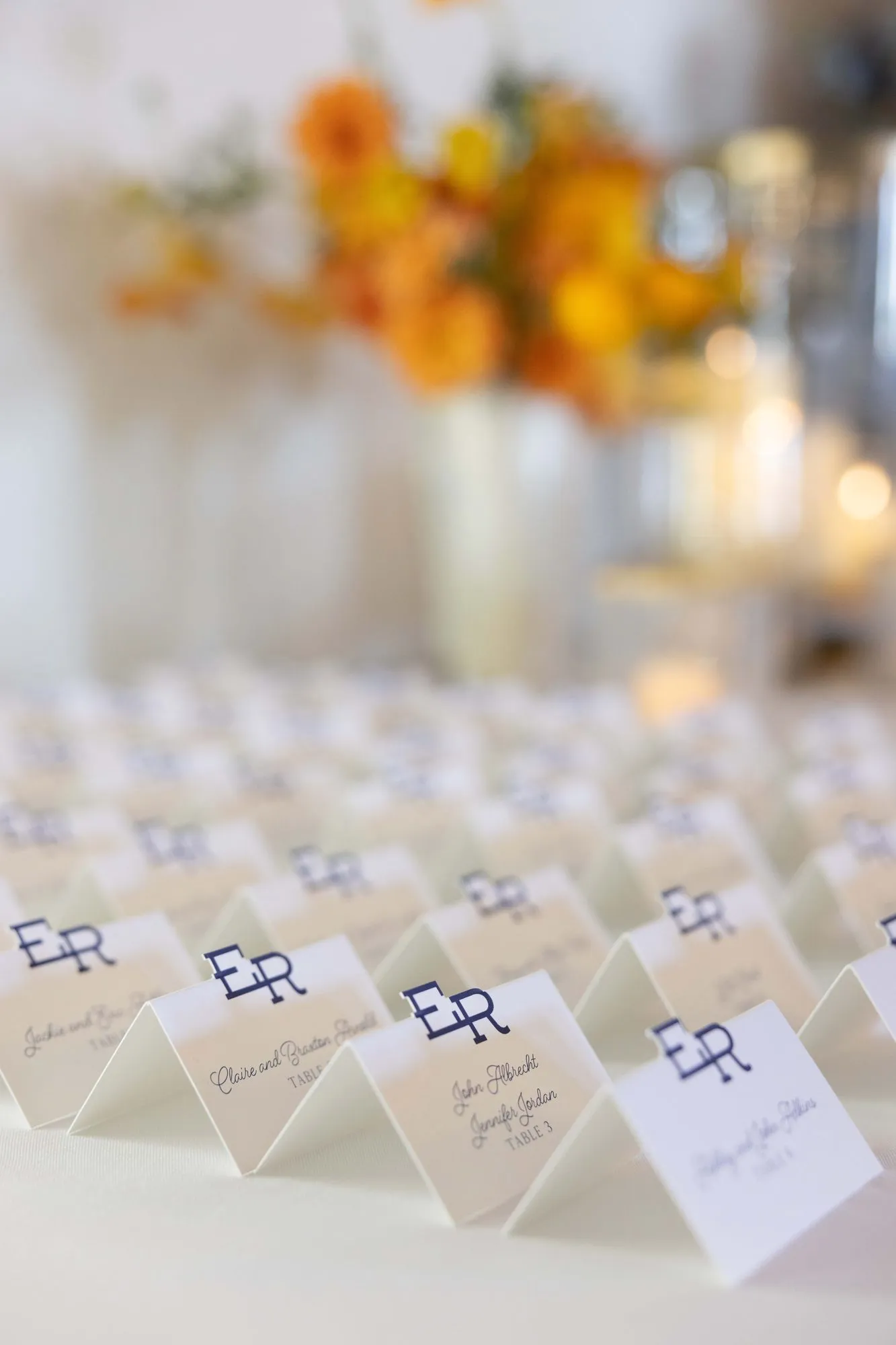 Rows of tented Eliza place cards with the navy monogram, set beside marigold florals, Mineral Wells, TX
