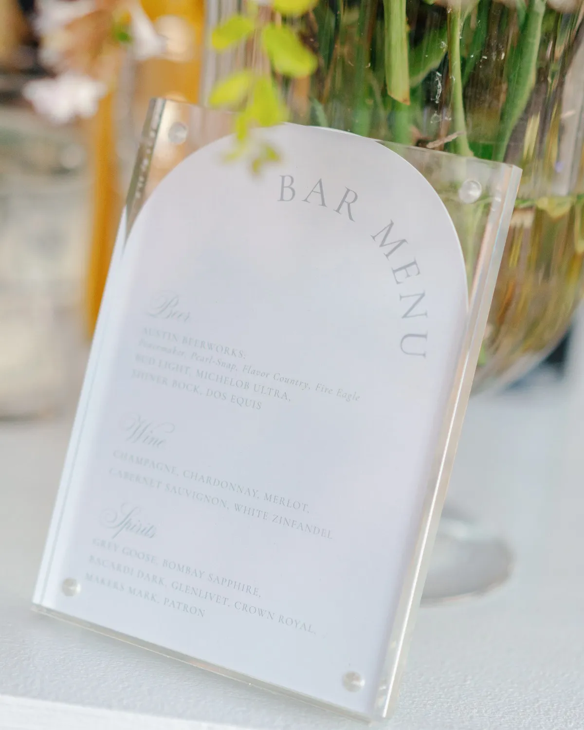 Arch die-cut Huang–Dentino bar menu in an acrylic stand, beer, wine, and spirits set in soft blue type, Austin, TX