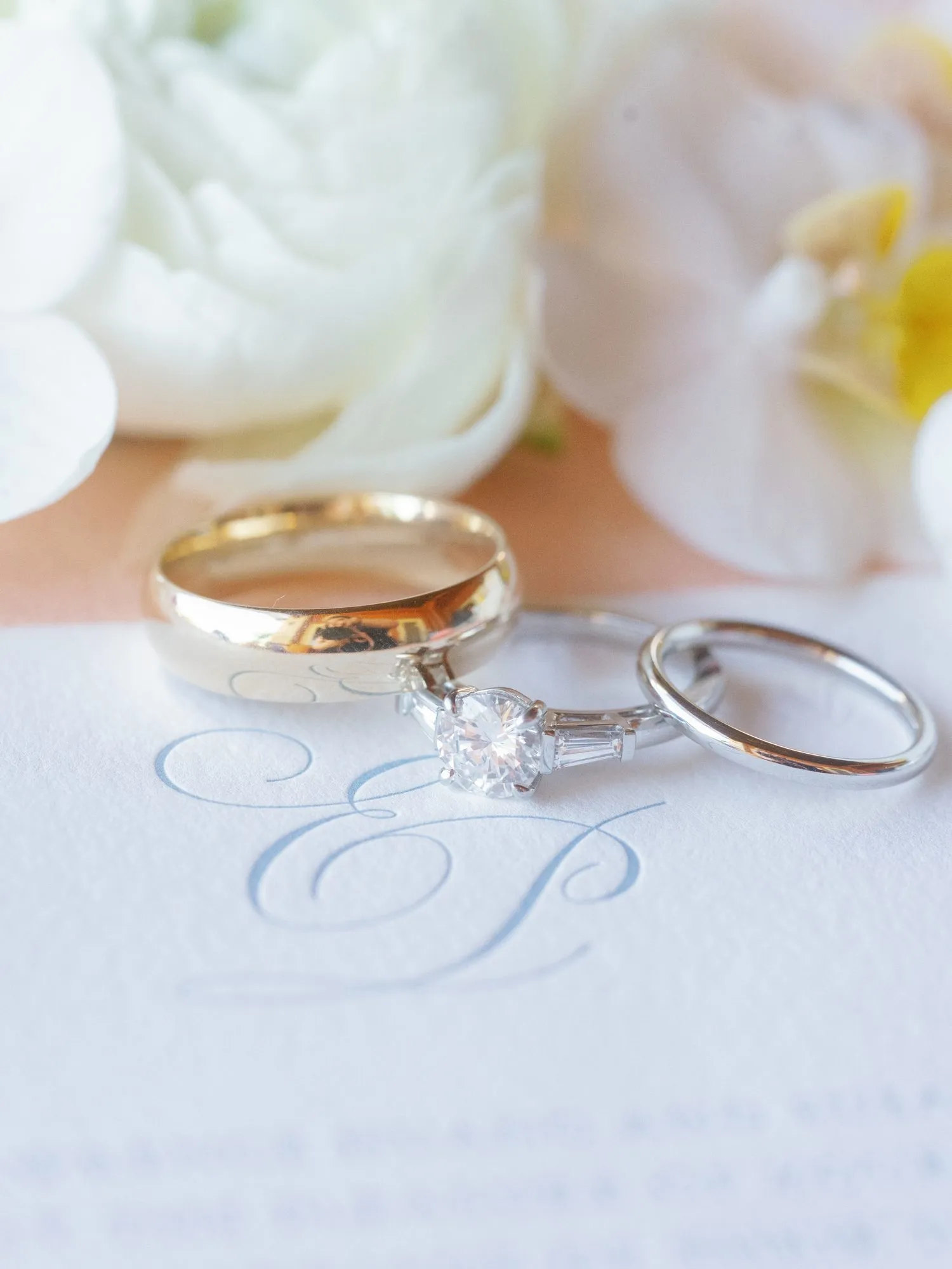 Three rings resting on the blind-embossed Huang–Dentino monogram on soft white cotton stock