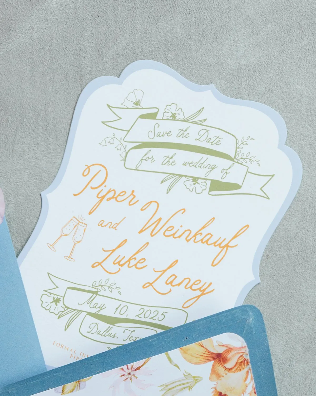 Laney die-cut save-the-date with a scalloped border, green banner illustrations, and orange script, Dallas, TX