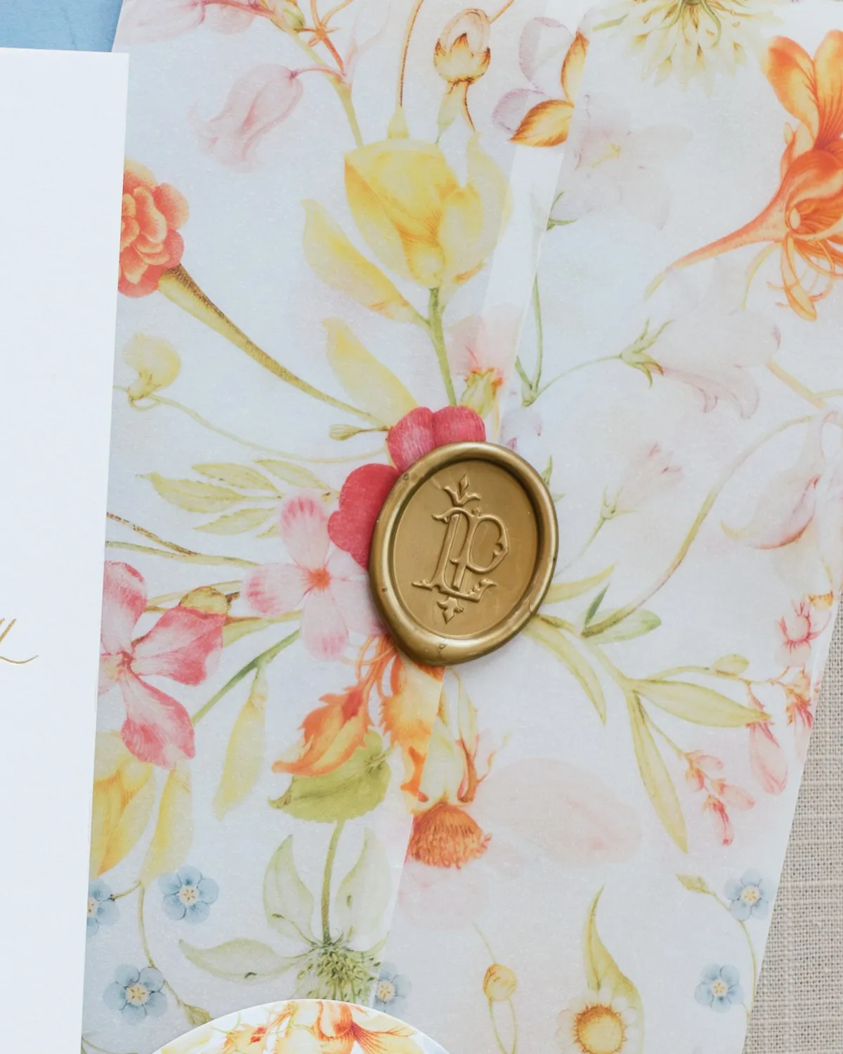 Gold wax seal with the Laney monogram closing a watercolor floral vellum wrap