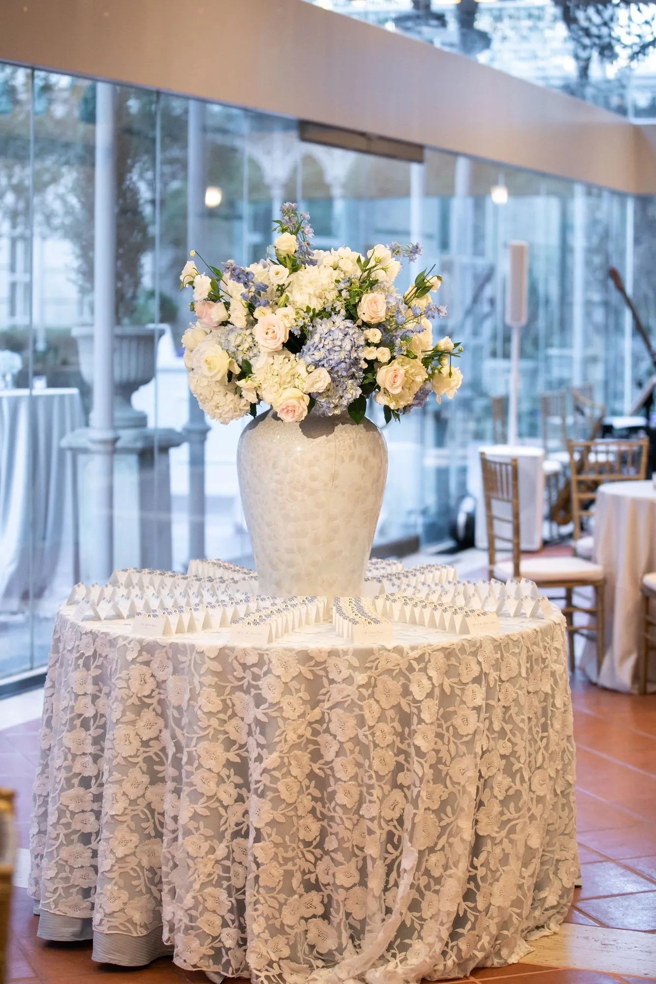 Orr escort card table: tented cards with blue floral edges arranged around a white urn of blue and blush florals