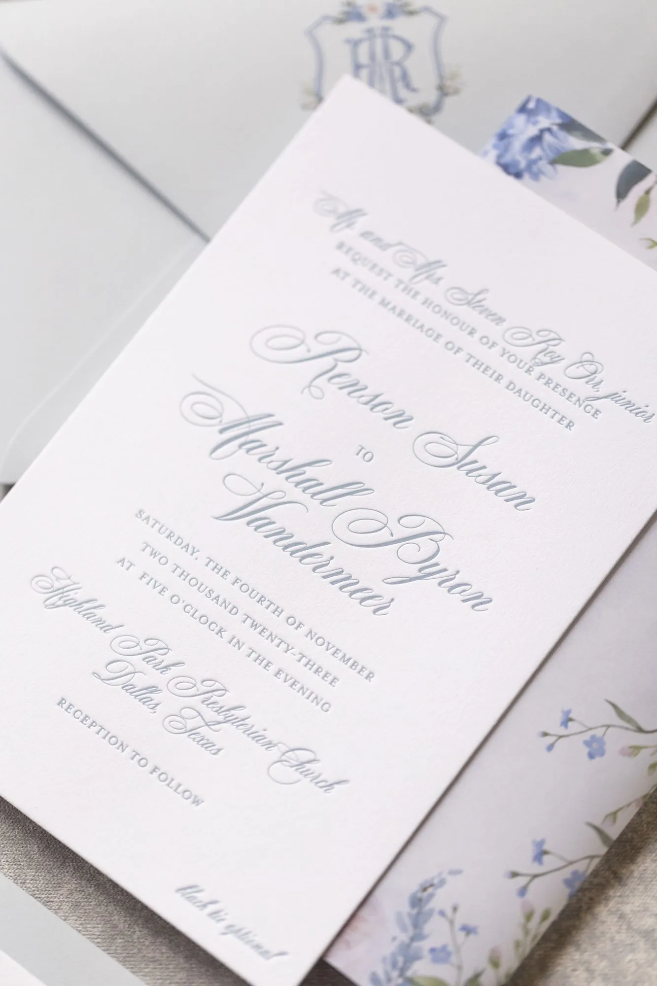 Raking-light detail of the Orr invitation showing letterpress impression and the blue monogram crest